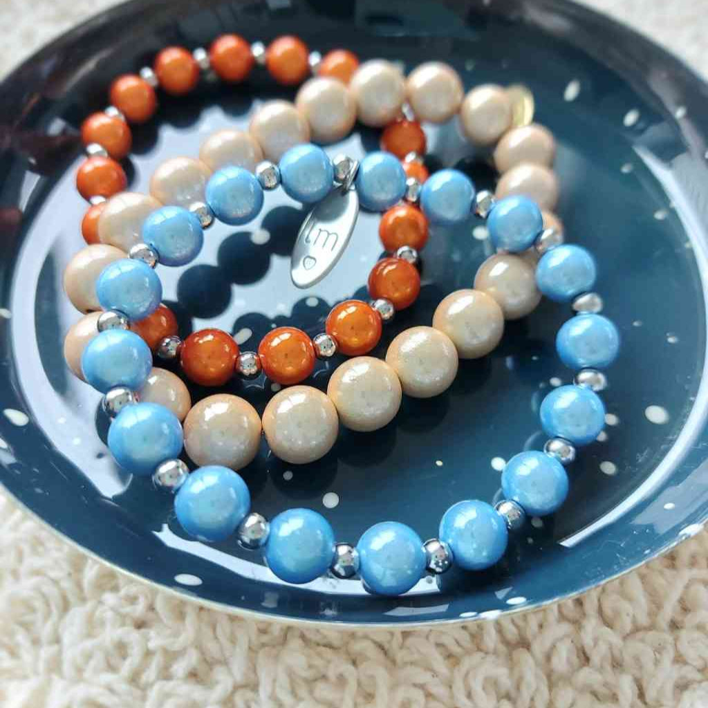 verschiedene perlenarmbaender, modeschmuck beige, orange, hellblau auf schale von strömshaga, alles erhältlich bei www.luiseundfritz.de
