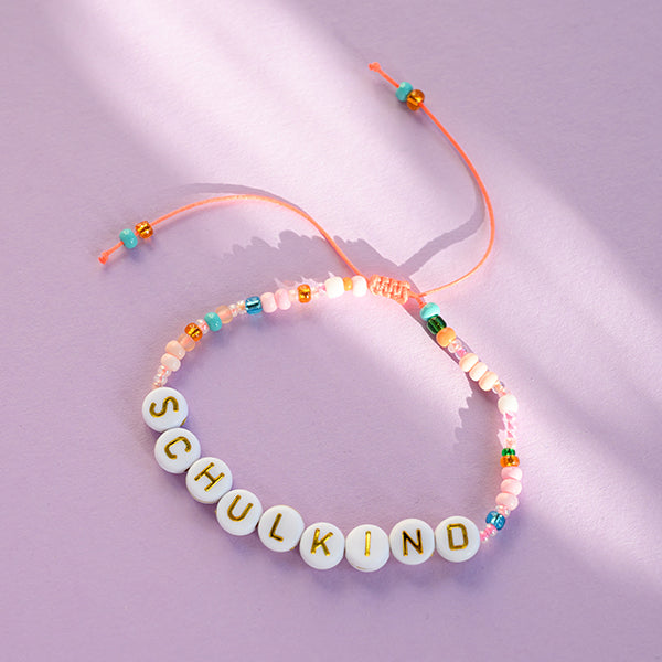 Perlenarmband SCHULKIND orange/rosa mit Buchstaben in gold inklusive blau gestreiftem, besticktem STOFFBEUTEL
